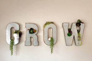 metal wall art spelling GROW with plants inserted within the letters