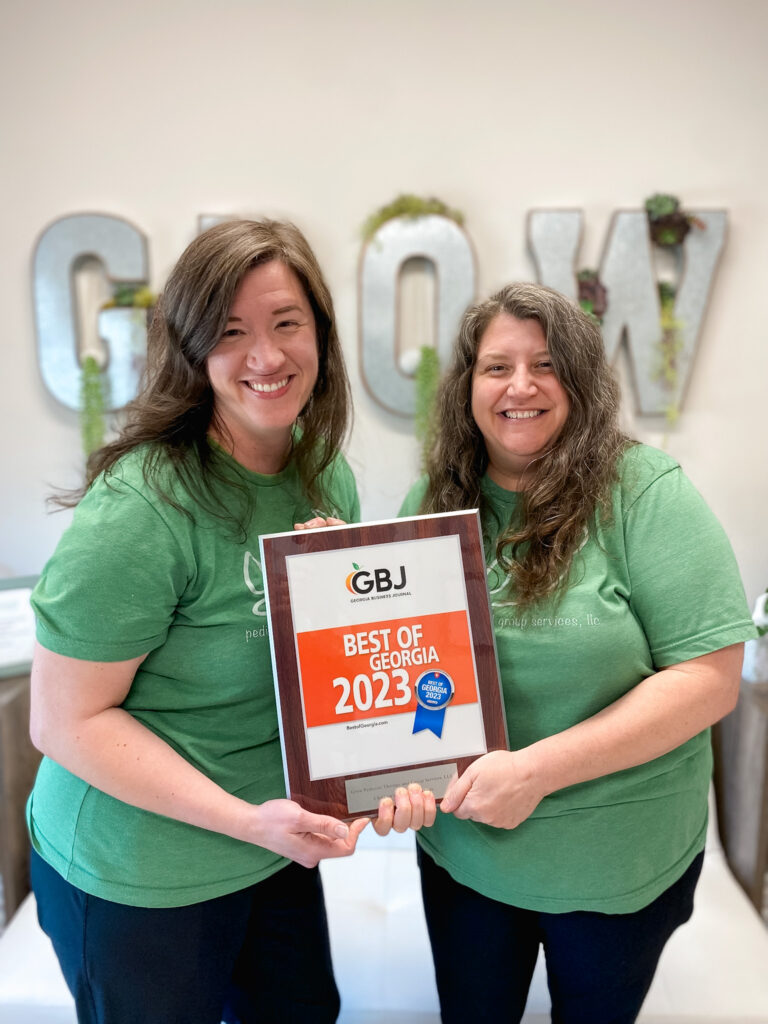 Co-owners Christy Clutter and Victorie Steed hold their Georgia Business Journal Best of Georgia 2023 award for children's therapy practices, earned by popular vote.